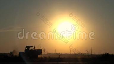 拖拉机在田野里的剪影，骑着车朝夕阳走去。 慢动作
